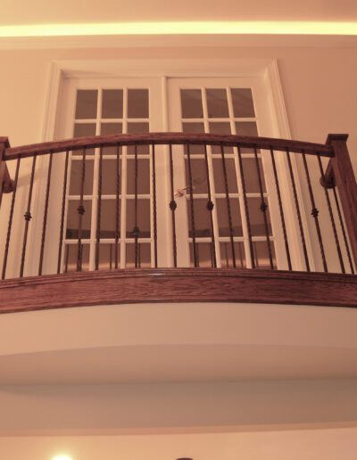 Interior balcony with wooden railing and glass door.
