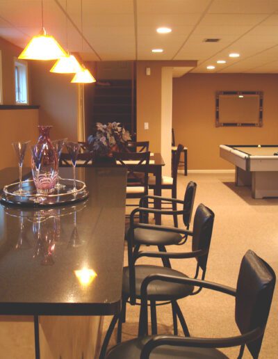 A modern finished basement with a bar area, seating, and a billiards table.