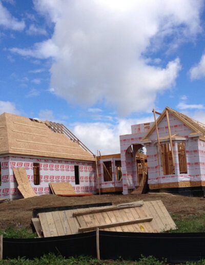 New residential homes under construction with wooden frames and partial roofing in progress.