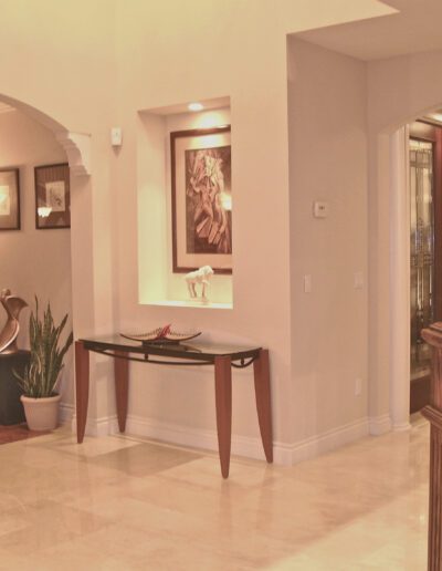 Elegant residential foyer with decorative art, a console table, and tiled flooring.