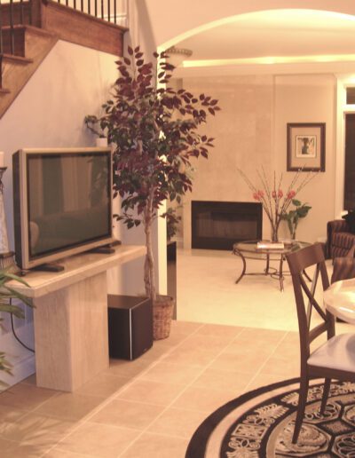 A well-lit living room with a staircase, a television set, and a fireplace.