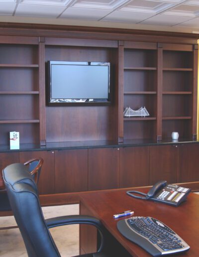 Modern conference room with a large wooden cabinet, flat-screen television, and a conference table with chairs.