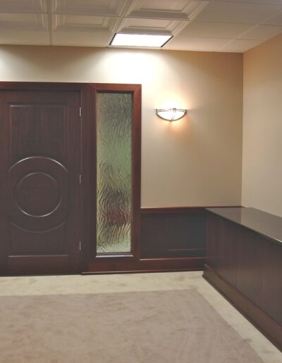 Modern conference room with double doors, wooden furnishings, and wall-mounted television.