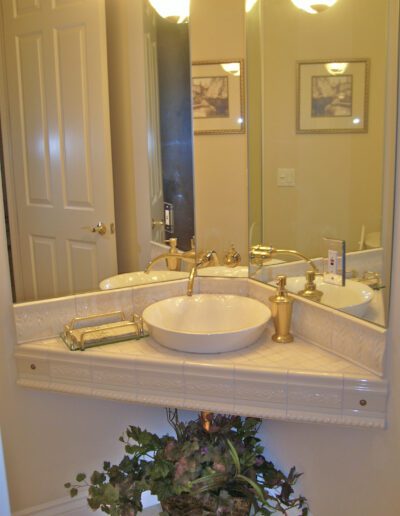 A neatly maintained bathroom with a white sink, gold fixtures, a mirrored medicine cabinet, and decorative elements.
