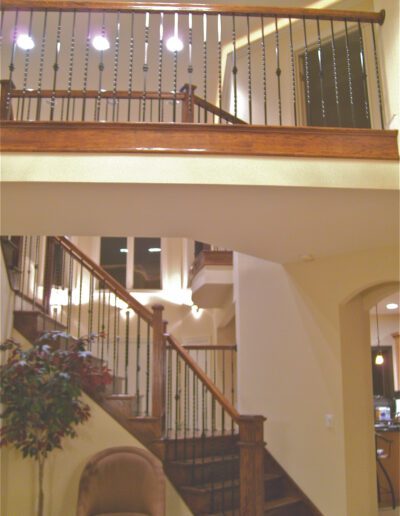 An interior view of a house featuring a wooden staircase leading up to a well-lit upper floor with railings.