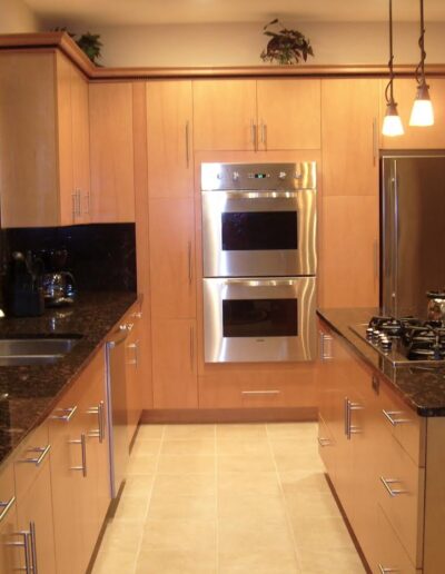 Modern kitchen with wooden cabinets, stainless steel appliances, and black granite countertops.
