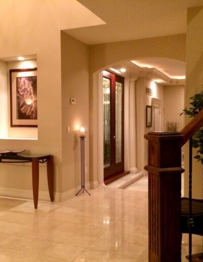 Elegant interior hallway with tiled floor, staircase, and warm lighting.