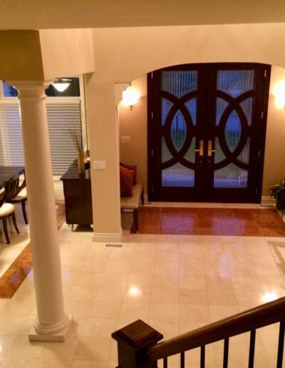 Elegant interior of a home showing a dining area, staircase, and decorative front door with warm lighting.