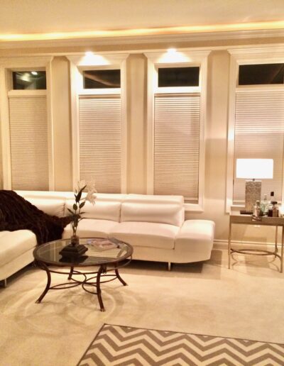 Elegant living room with white sectional sofa, glass coffee table, and warm ambient lighting.